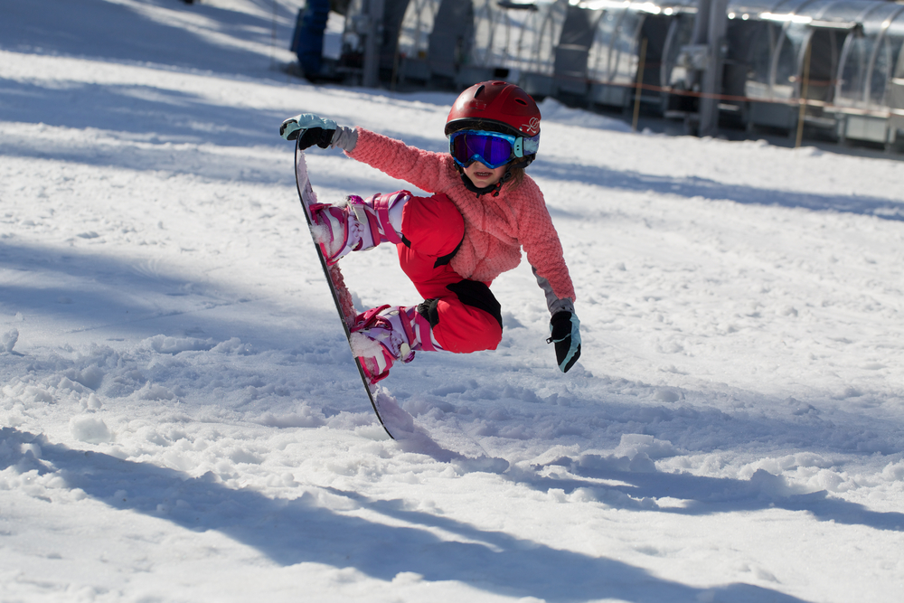 Little,Cute,Girl,Snowboarding,Making,A,Tricks,At,Ski,Resort